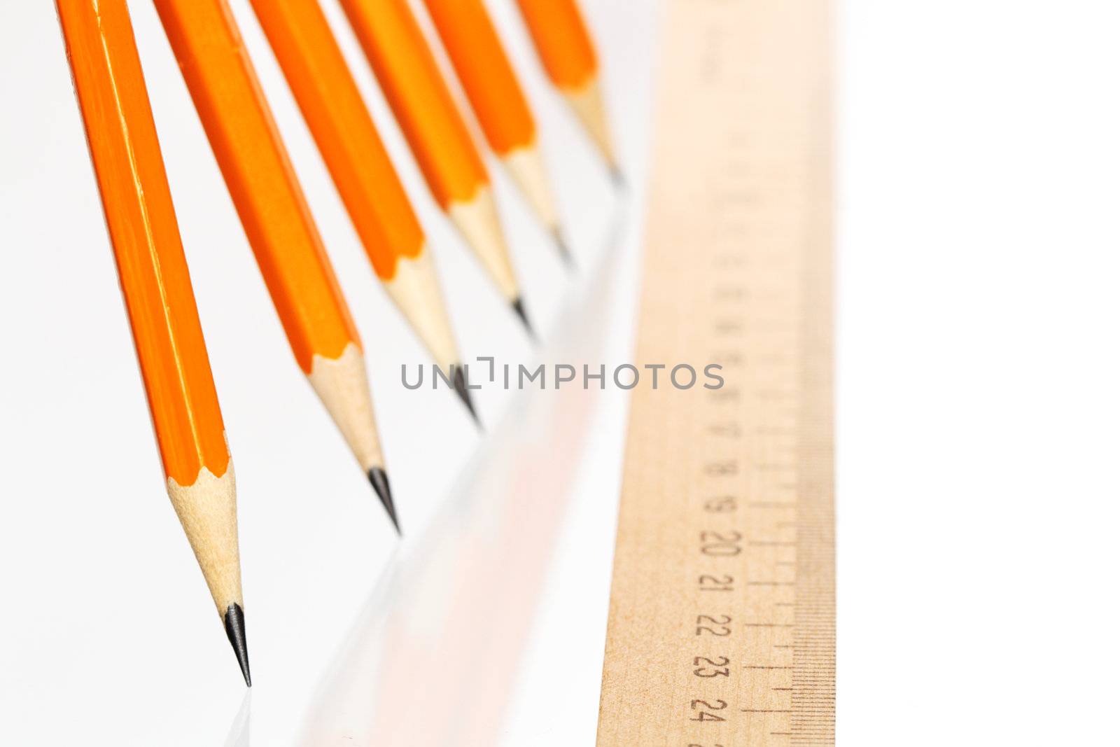 Few wooden yellow pencils in a row and ruler on white background