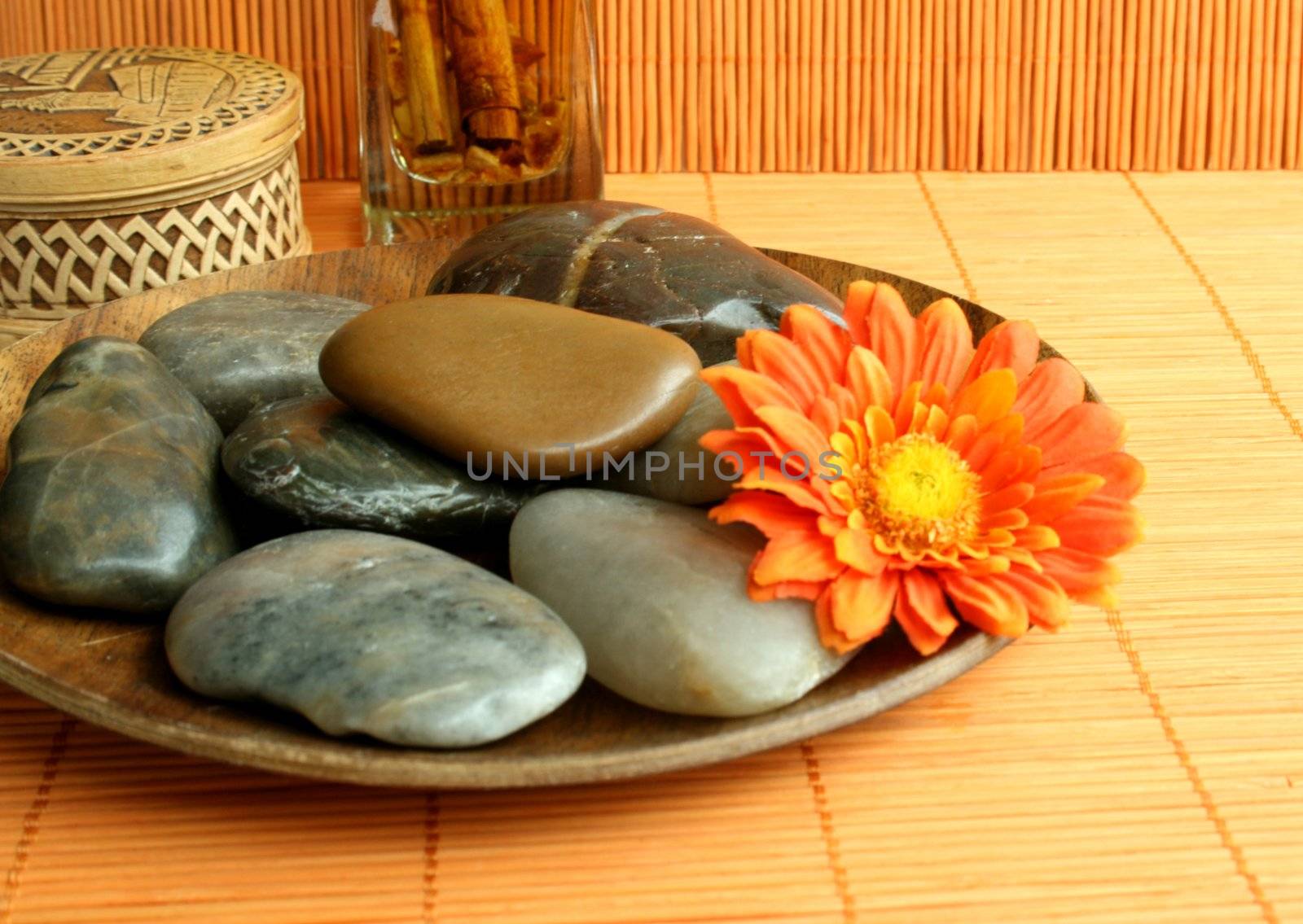Stones lay on a brown plate and a bright flower