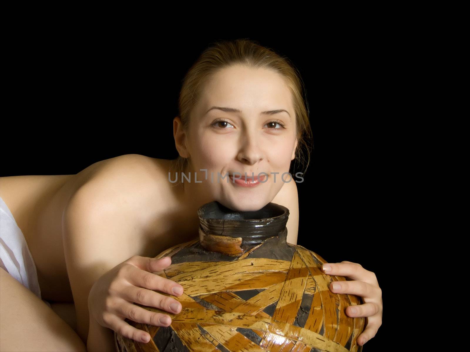 Young nudity girl with jug on black. Isolated by Jim
