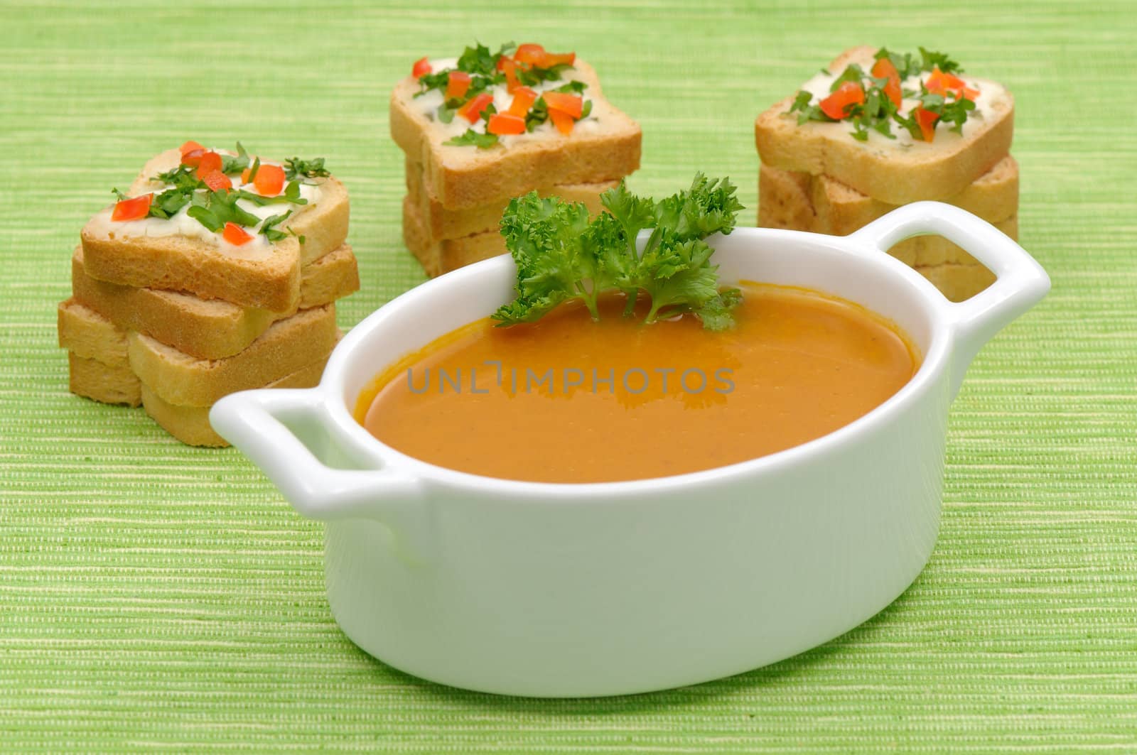 Bowl of vegetable soup with rusks on green background