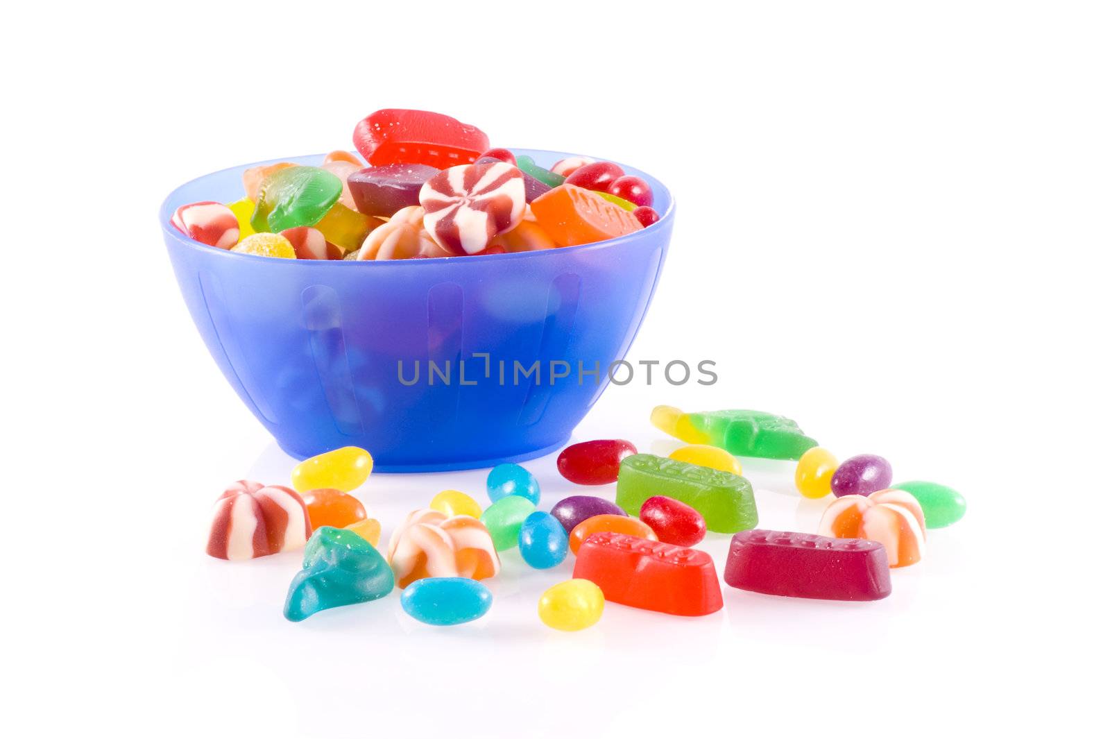 Blue bowl with different kinds of colorful candy isolated on white.