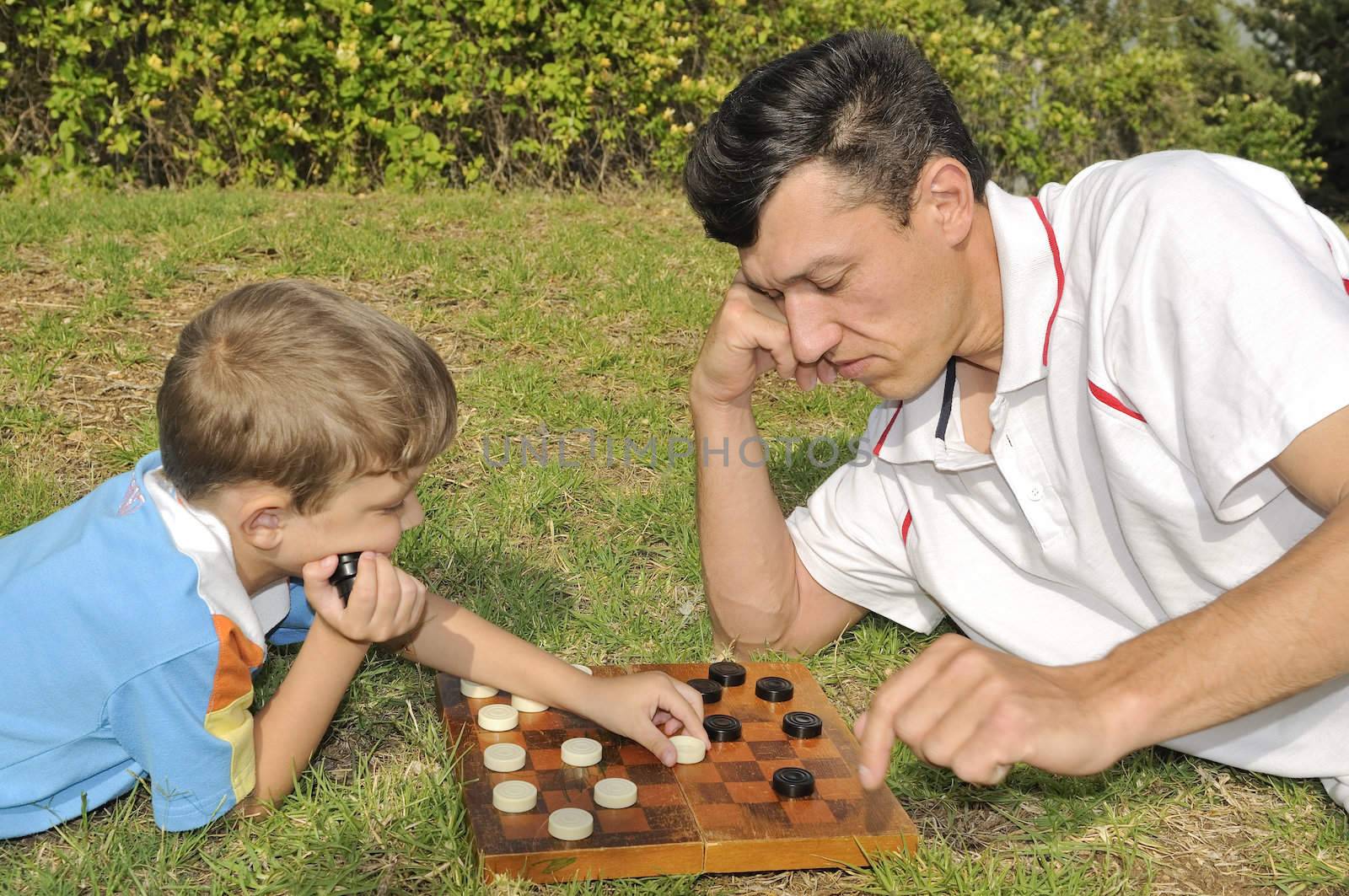 Father and the son play checkers(blocks) on the nature