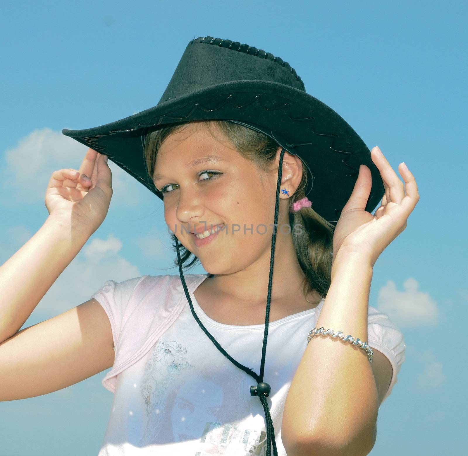 The girl happily smiles, tries on a hat and poses for the photographer