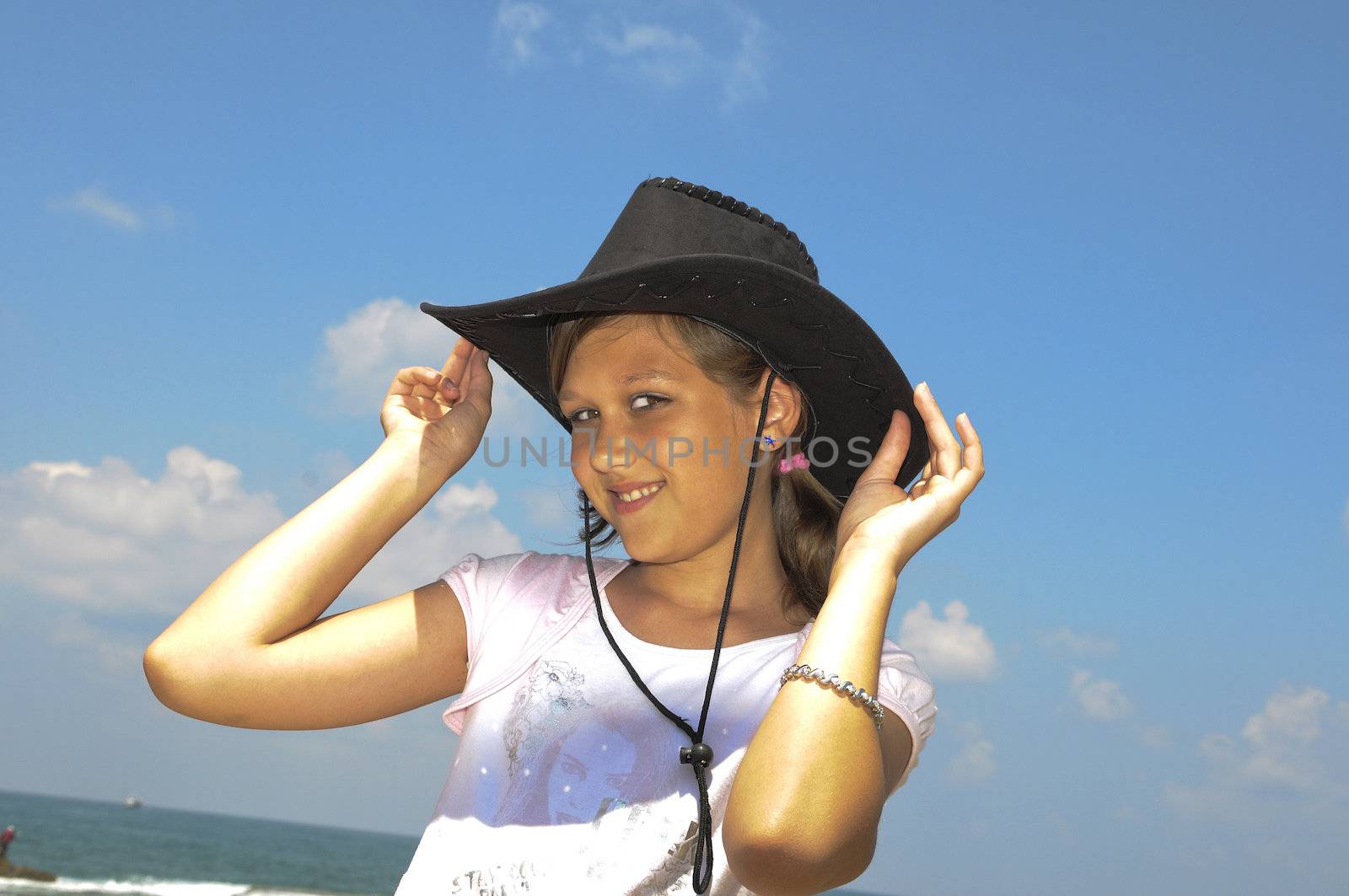 The girl happily smiles, tries on a hat and poses for the photographer