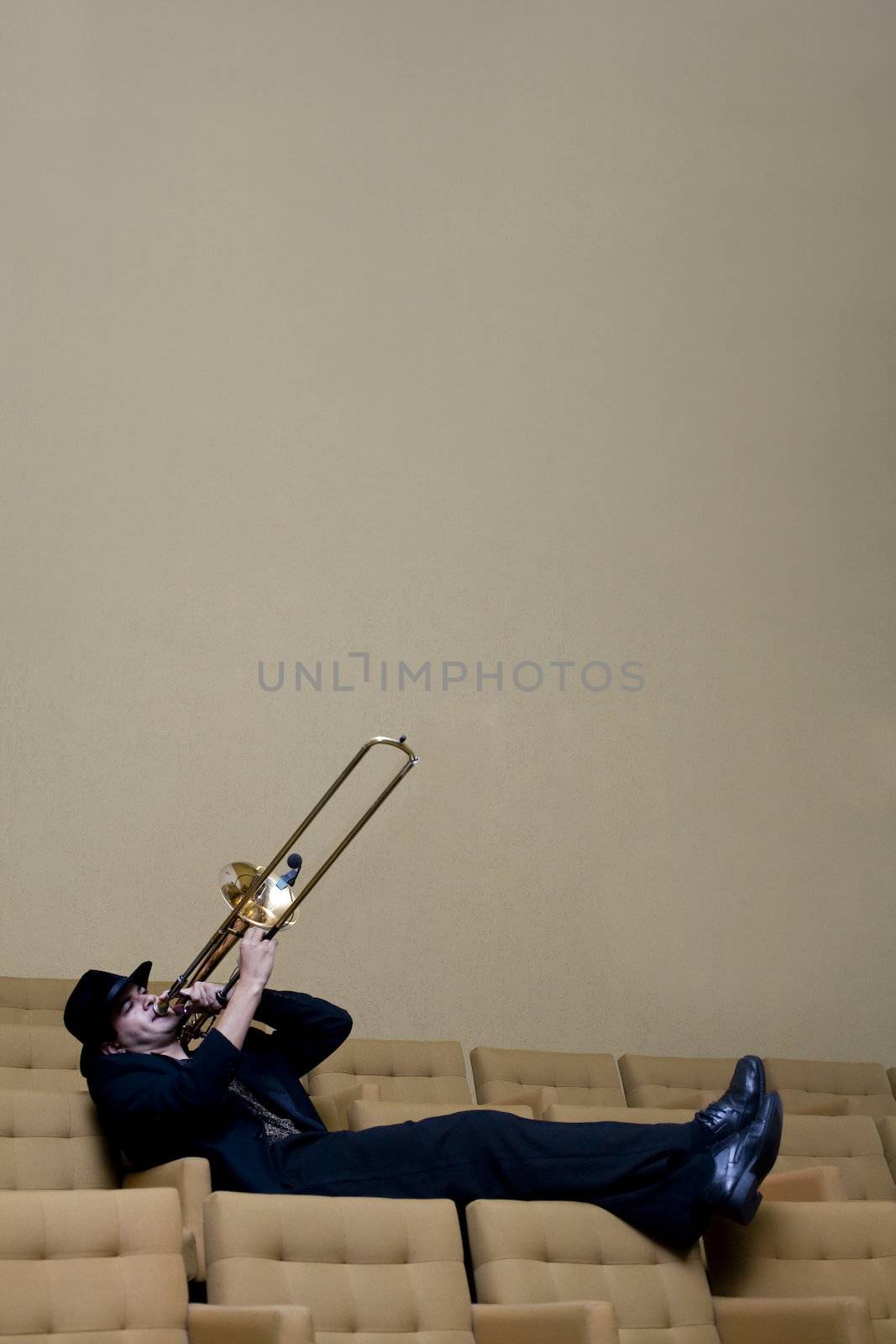 A trombonist in a black suit and yellow background.