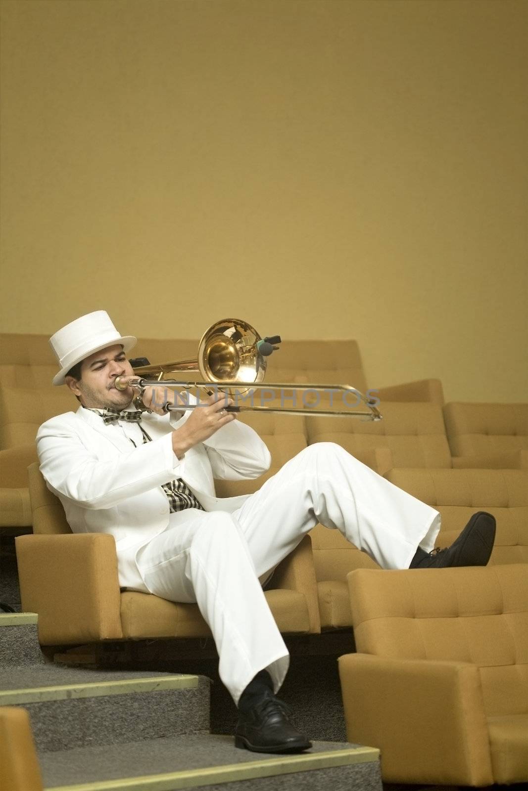 A trombonist in a white suit and yellow background.