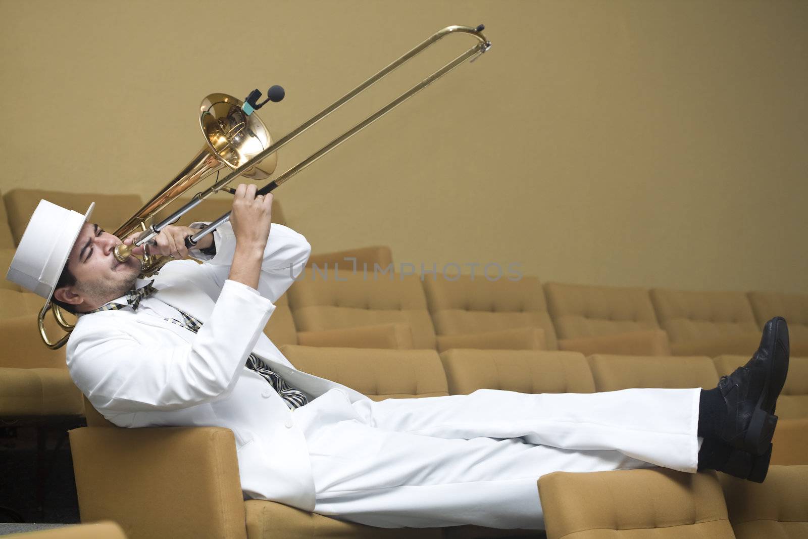 A trombonist in a white suit and yellow background.