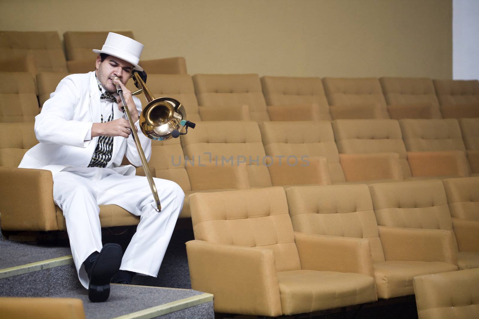 A trombonist in a white suit and yellow background.
