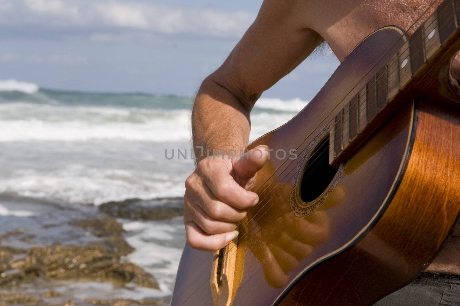 playing guitar against a backdrop of the sea
