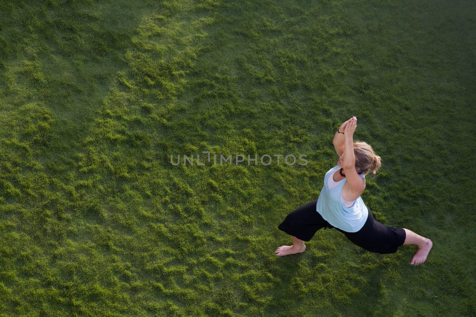 Woman doing yoga in the grass. Shot from above.