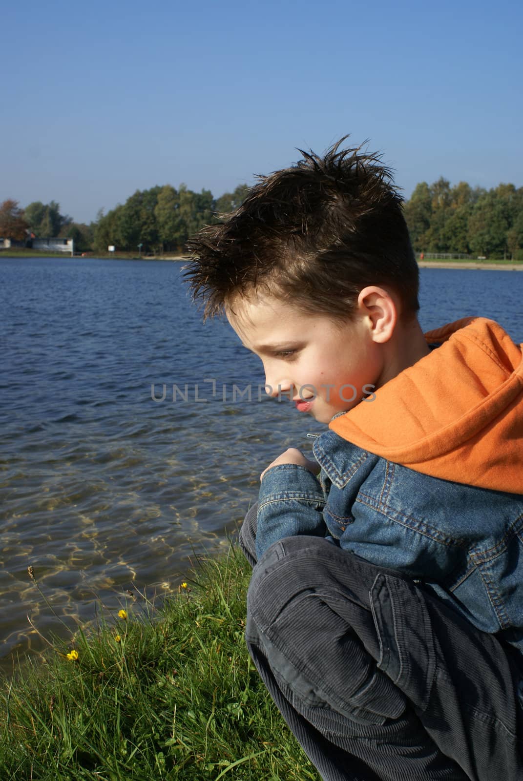 Boy sitting in grass enjoying the lake.