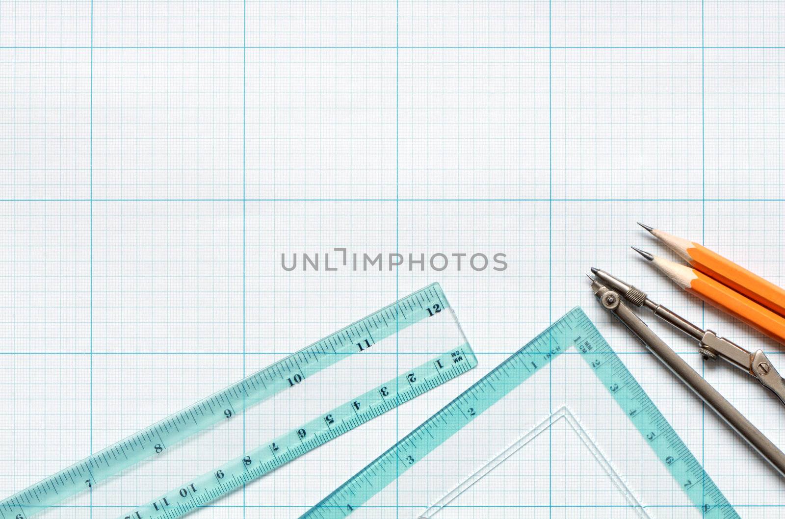 Divider, pencils and rulers on blue graph paper background