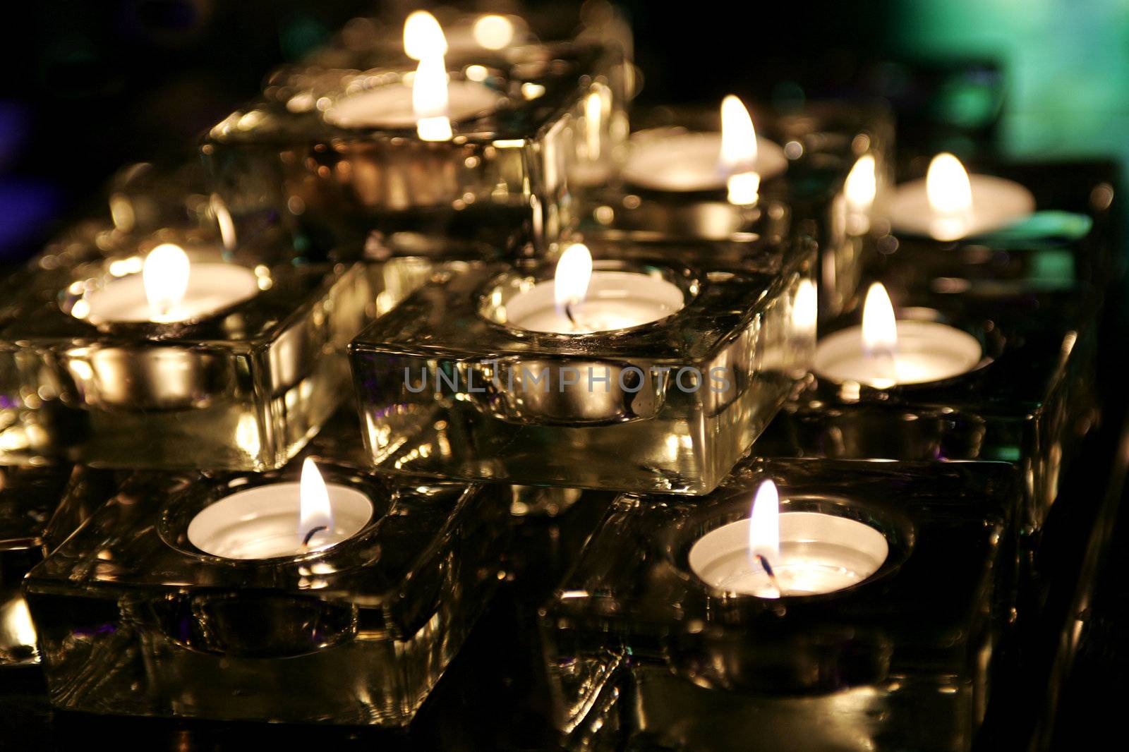 Romantic tea light candles burning in darkness.