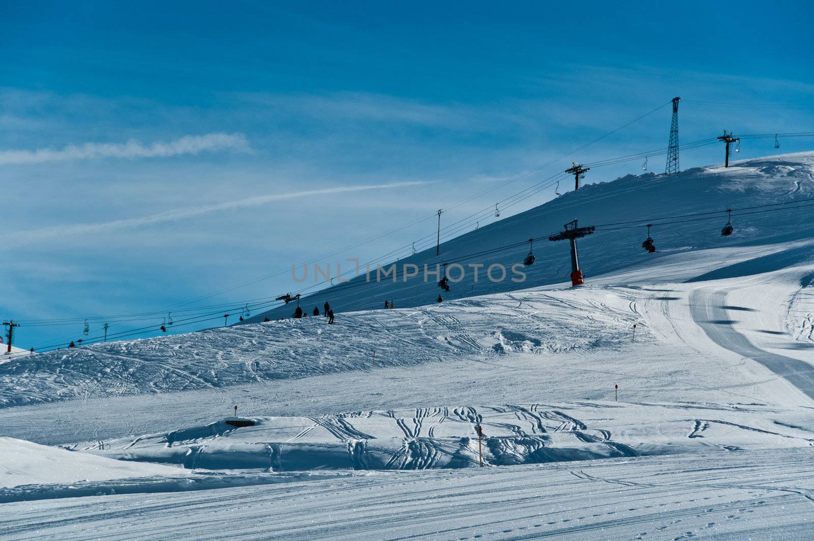 Pretty empty ski piste with chairlifts in the background - shot in Livigno, Italian Alps