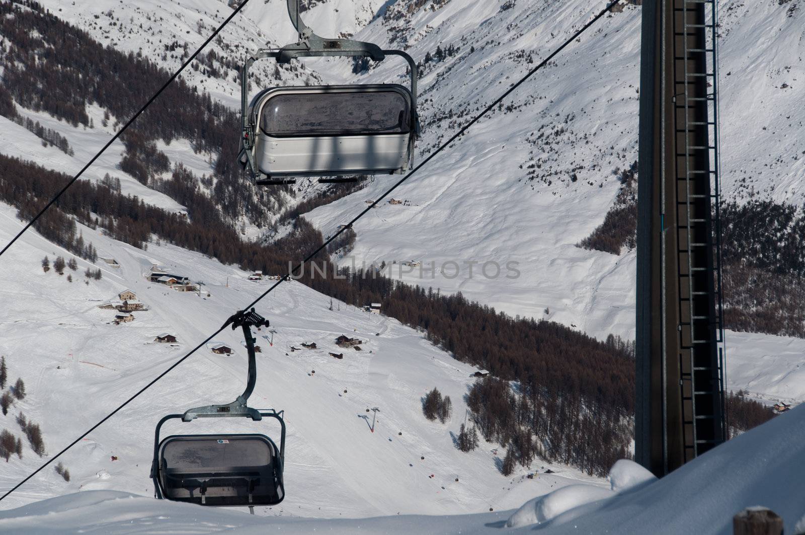 Chairlifts with ski slopes and skiers in the background - shot in Livigno, Italian Alps