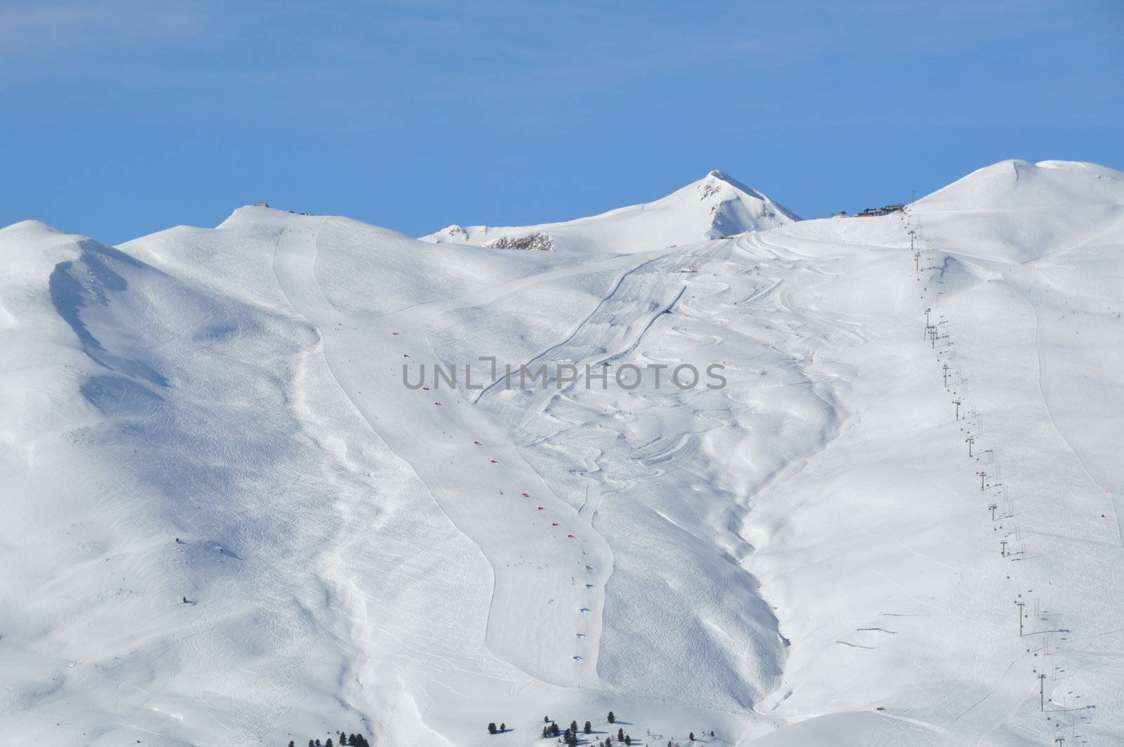 View on a steep skking mountain with two slopes, skiers and lifts - shot in Livigno, Italian Alps