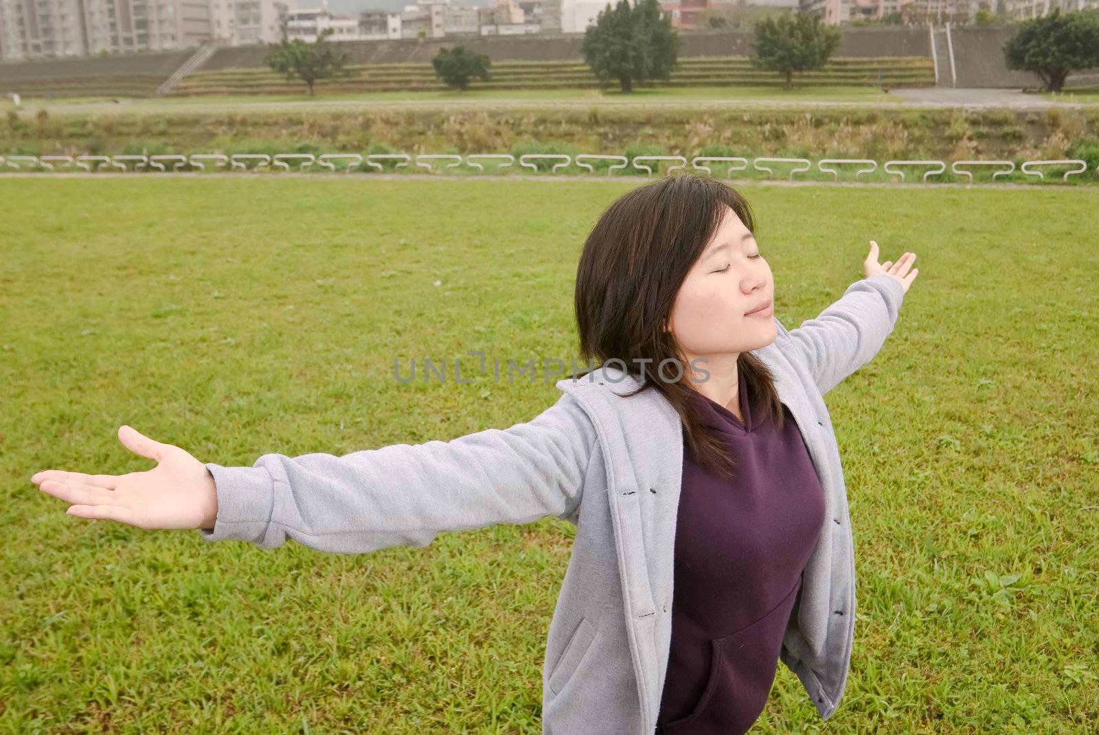 Freedom expression of Asian woman with open arms and closed eyes in outdoor of park of city.