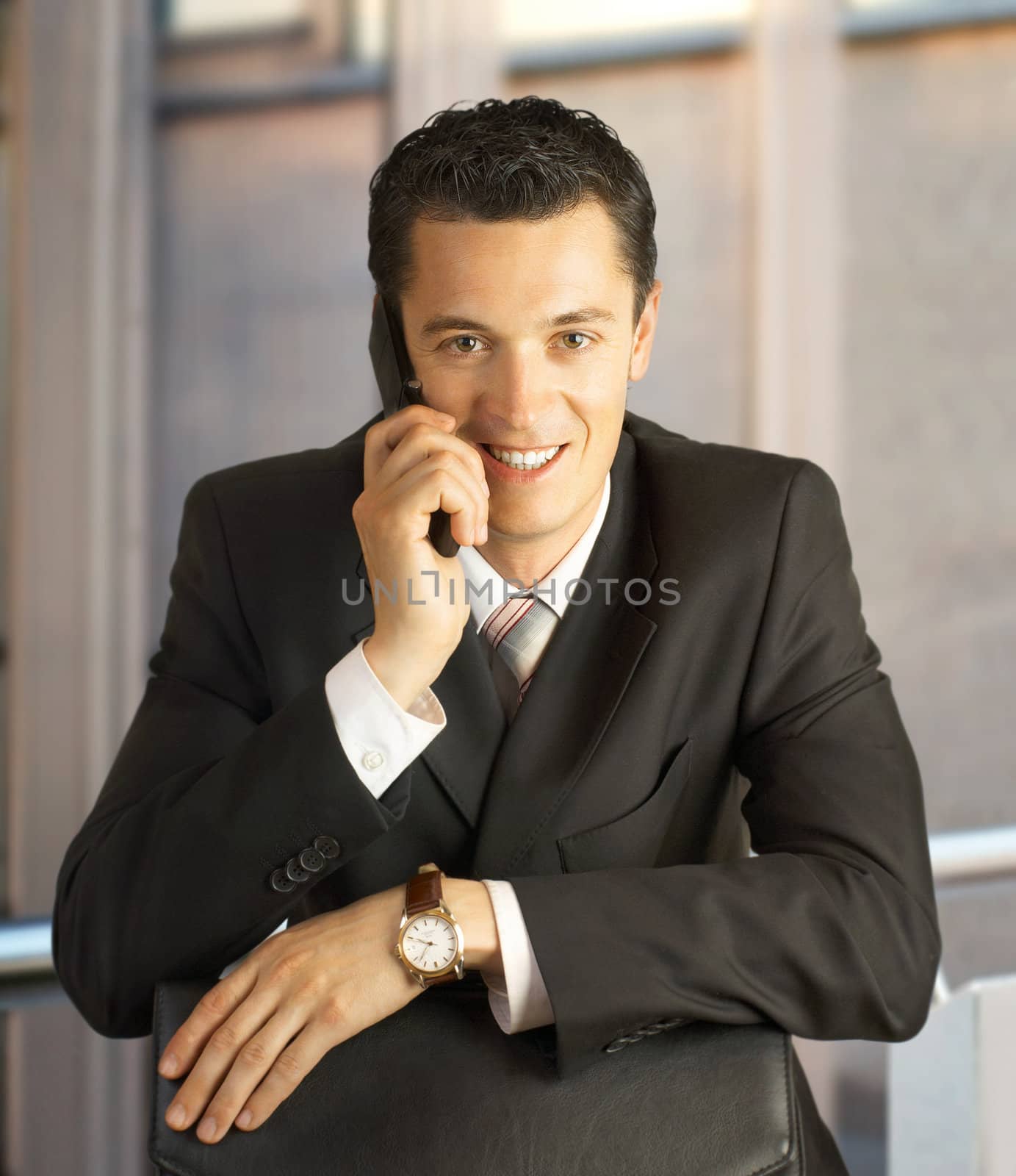 Businessman outside a modern building smiling with phone.