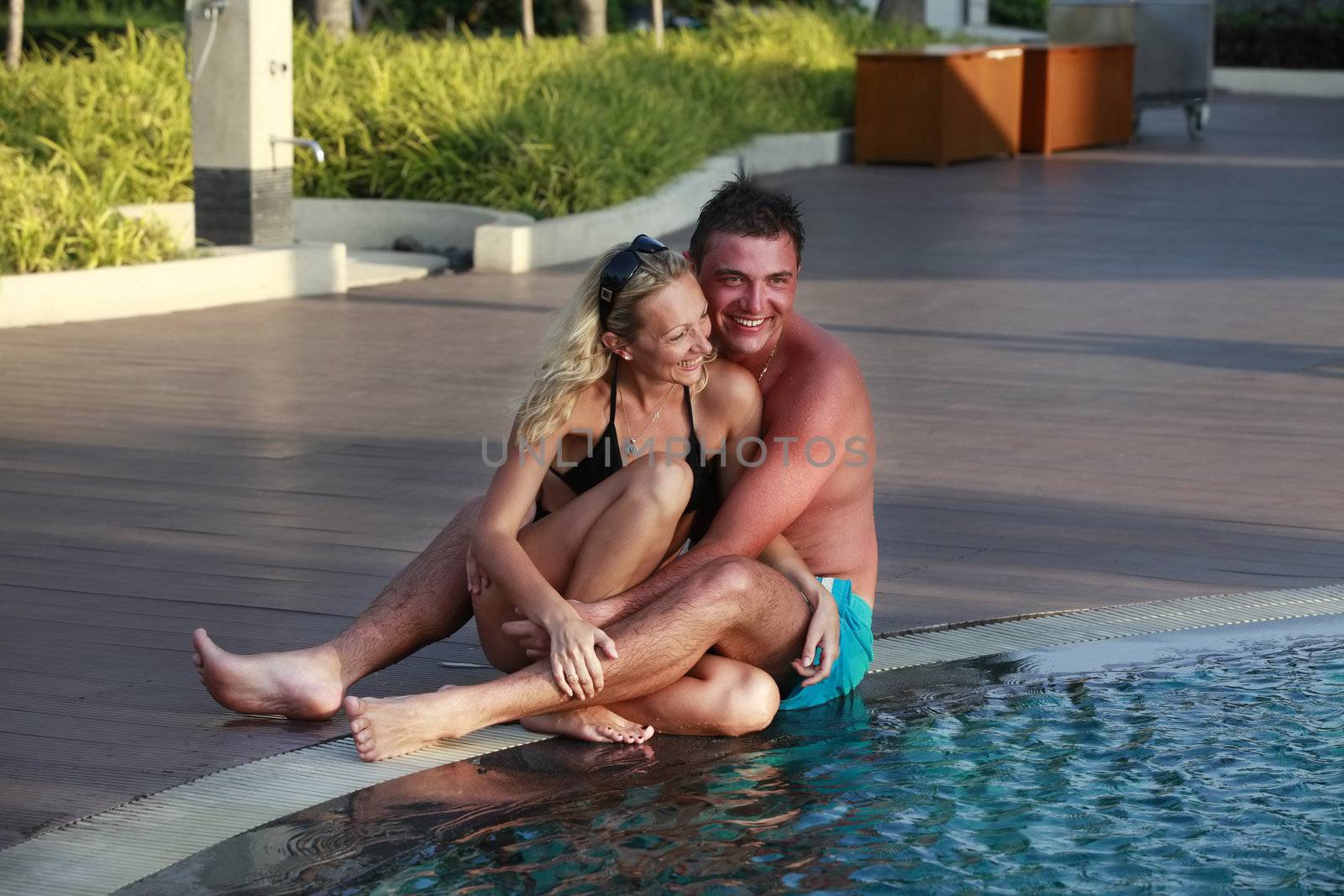 Beautiful lovers relaxing and embraces and kisses in swimming pool