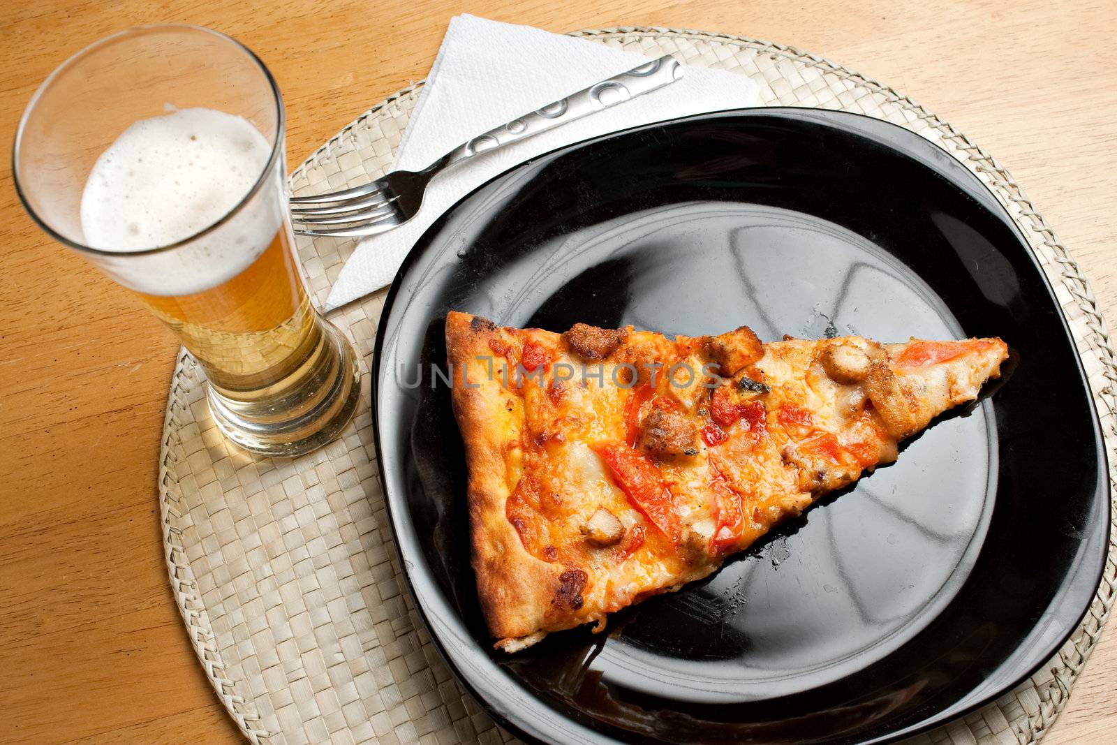 A single slice of buffalo chicken pizza and a glass of golden lager beer.  The perfect weekend take out dinner.