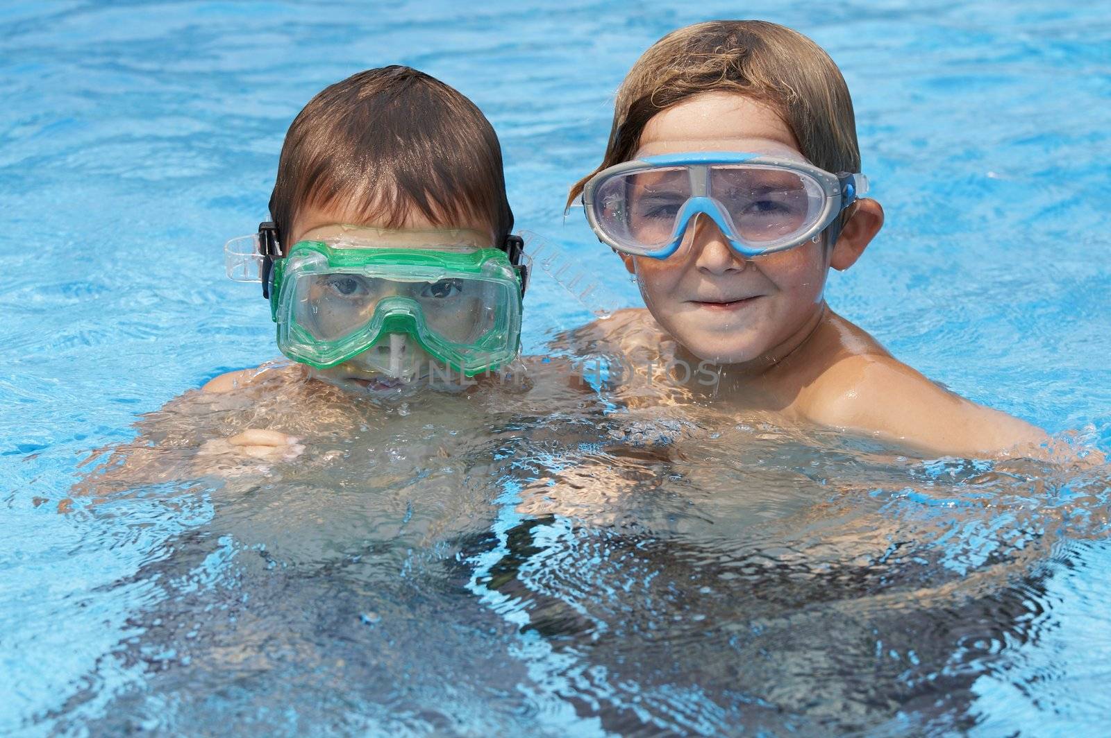 two young boys in pool with goggles on
