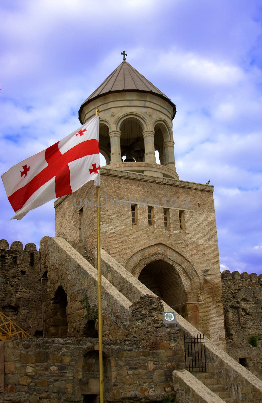 Georgian national red flag over orthodox church and blue sky