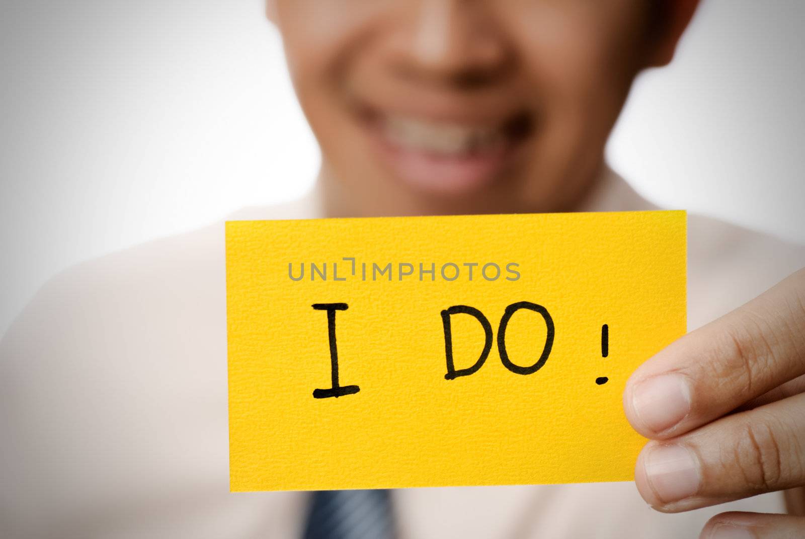 Businessman holding yellow card showing words �V I do.