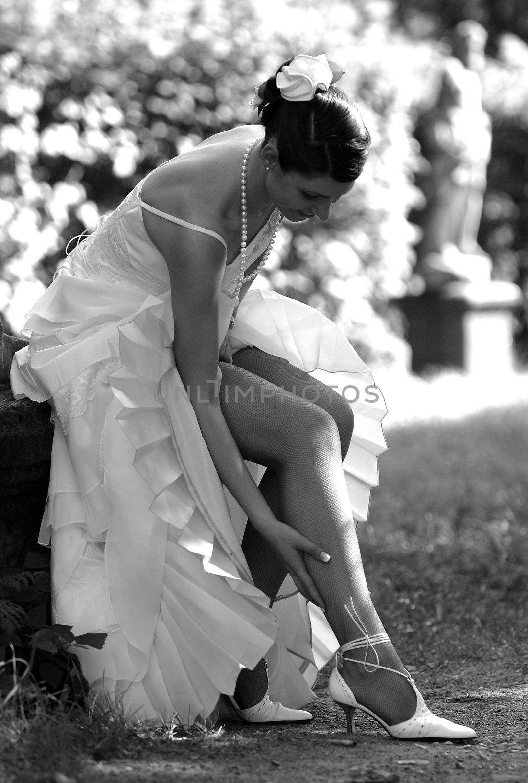 Beautiful bride in wedding dress adjusting her stockings.