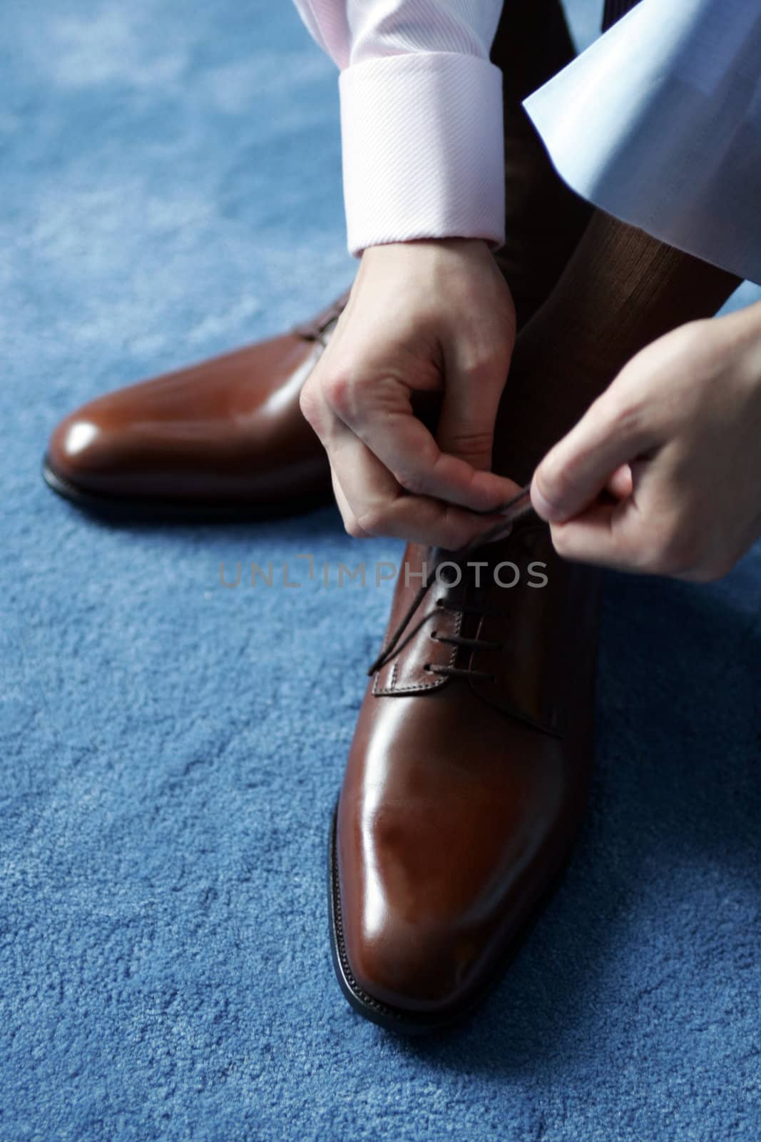 Businessman tying his shoes as he gets dressed for work.