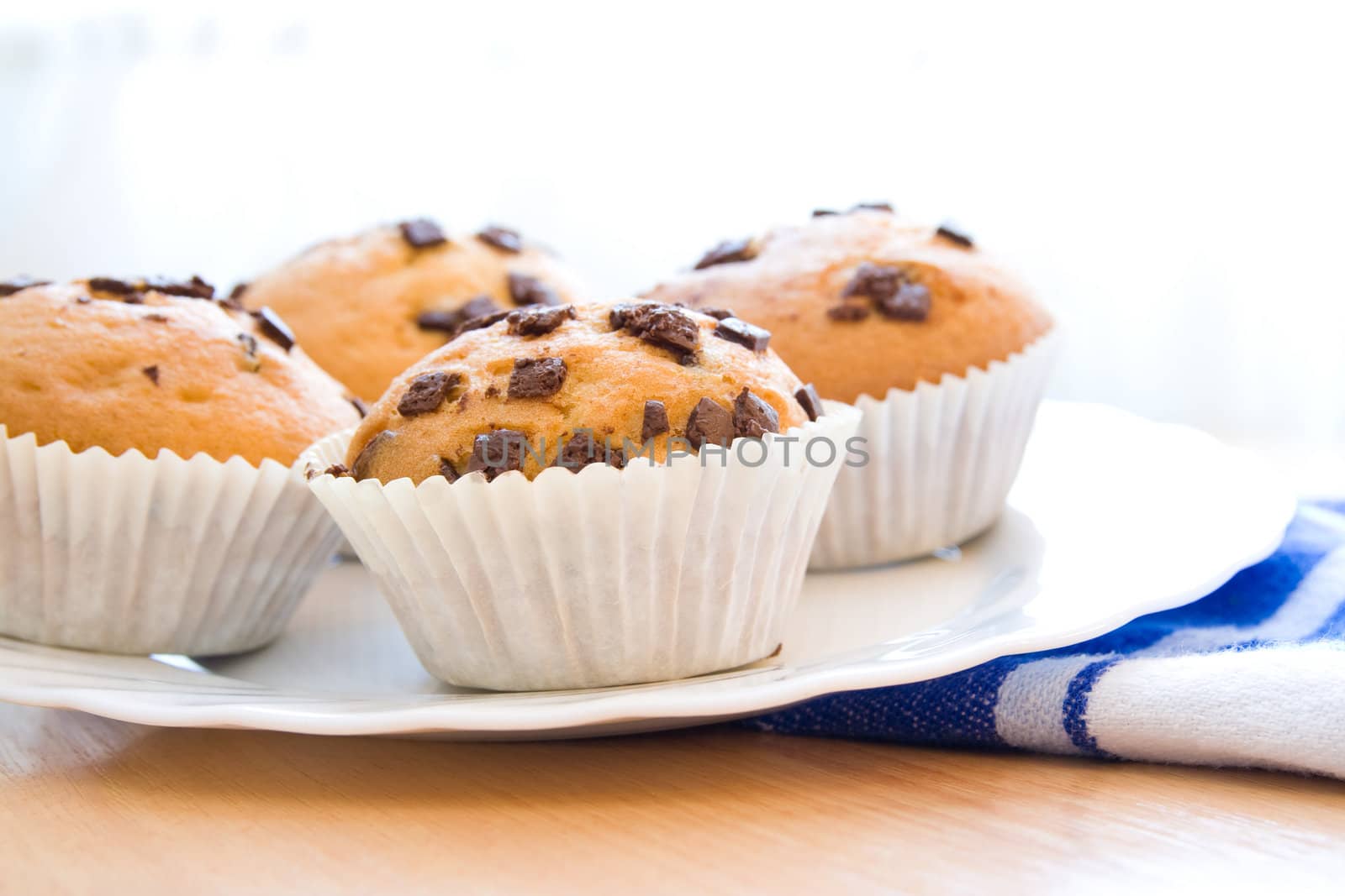 Four chocolate muffins on plate prepared for breakfast.