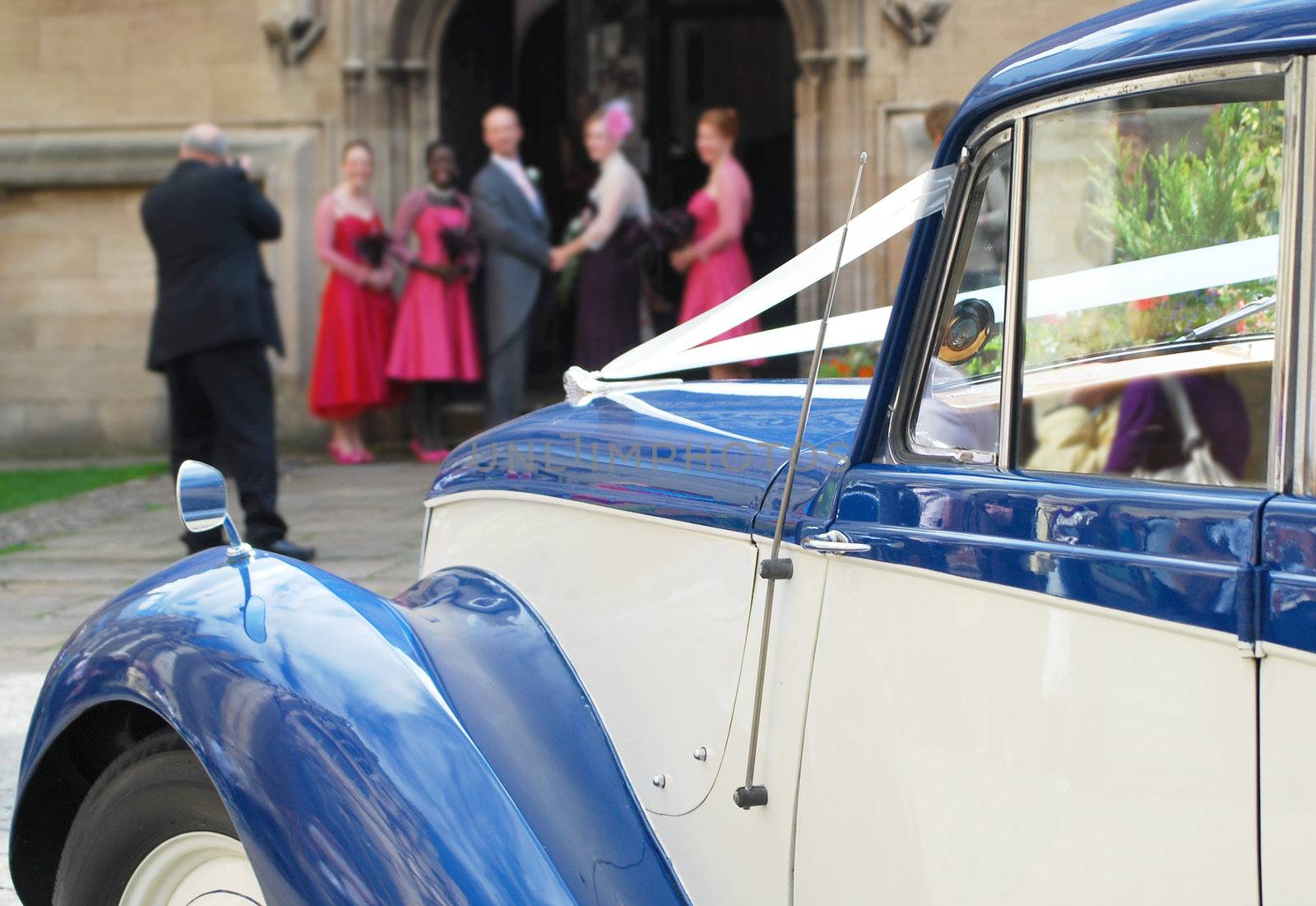 Vintage wedding car with wedding party in background