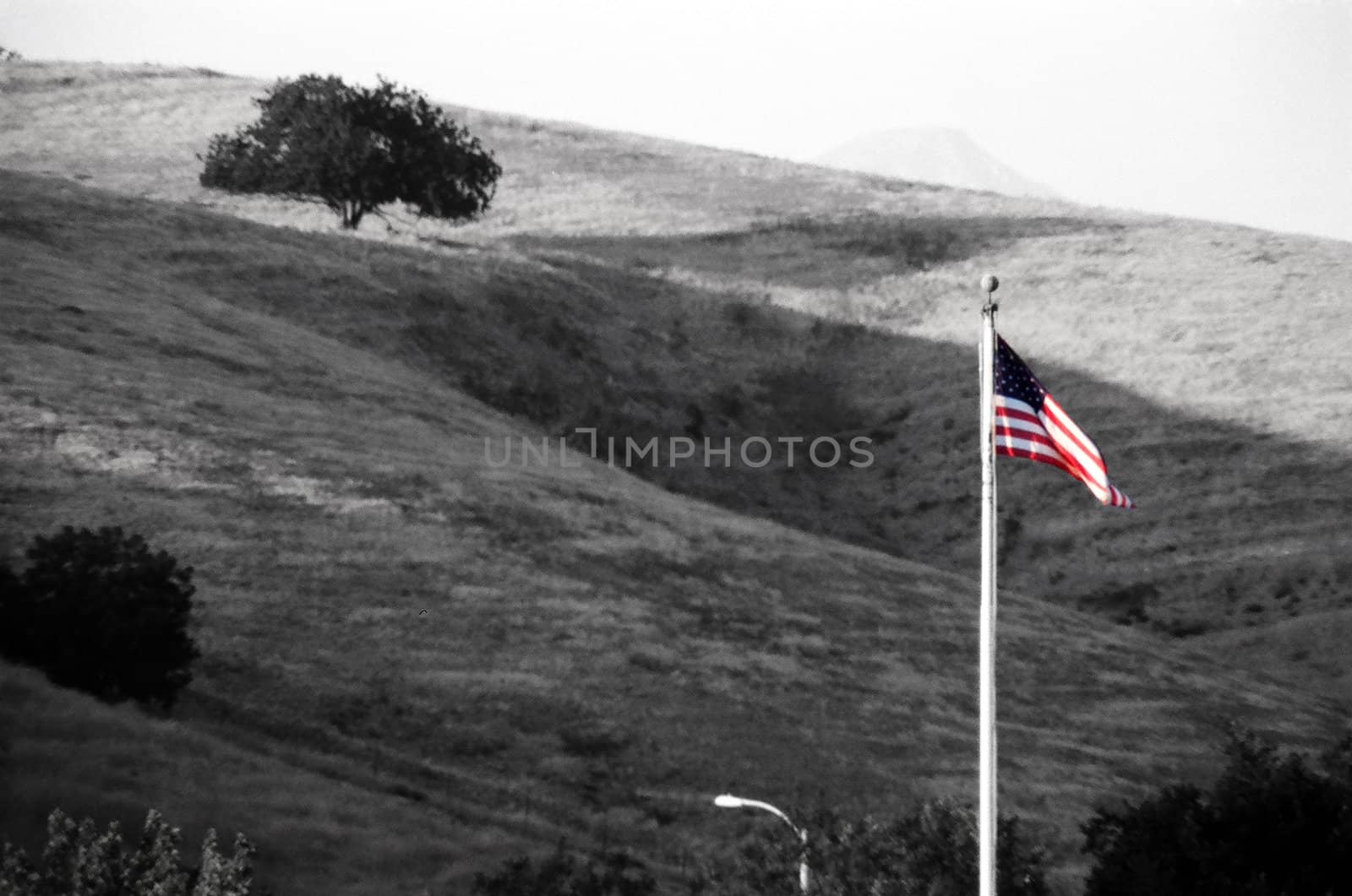 a grayscale coversion with the American flag re-colorized. Rolling hills in the background.