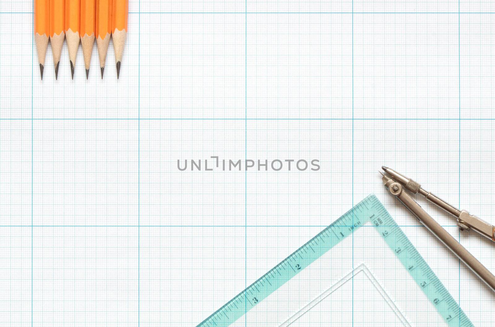 Divider, pencils and ruler on blue graph paper background