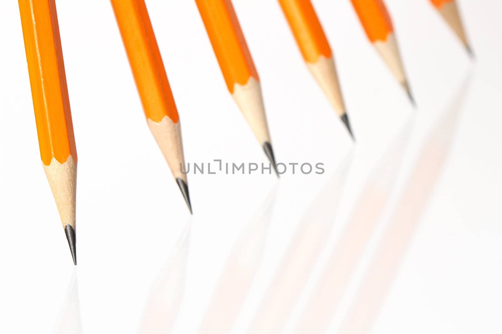 Few wooden yellow pencils standing in a row on white background