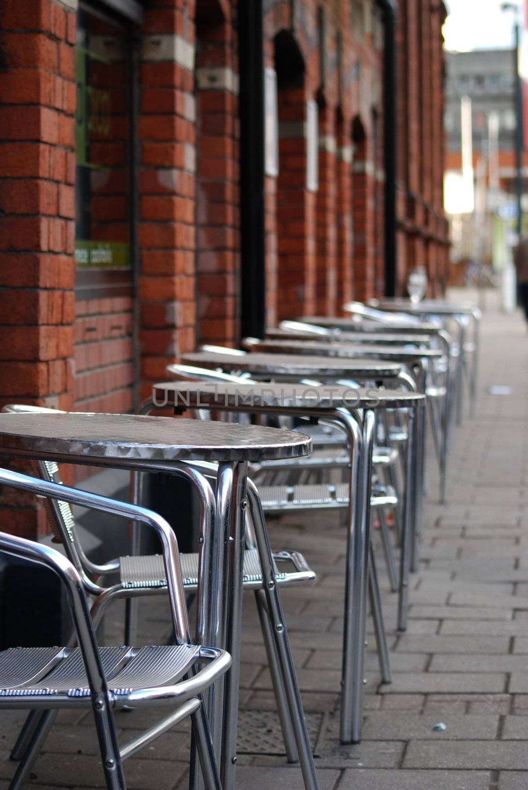 tables and chairs on the street in front of a restaurant