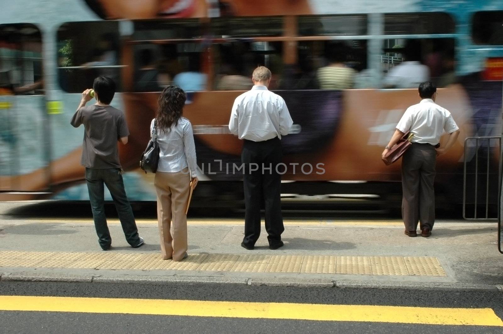 People in Hongkong waiting for green light, tram passing.