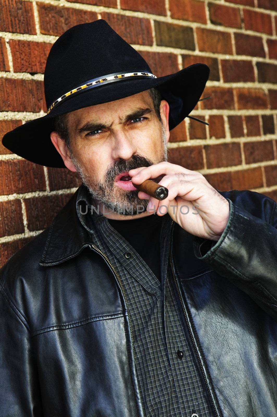 Man with beard in cowboy hat smoking cigar