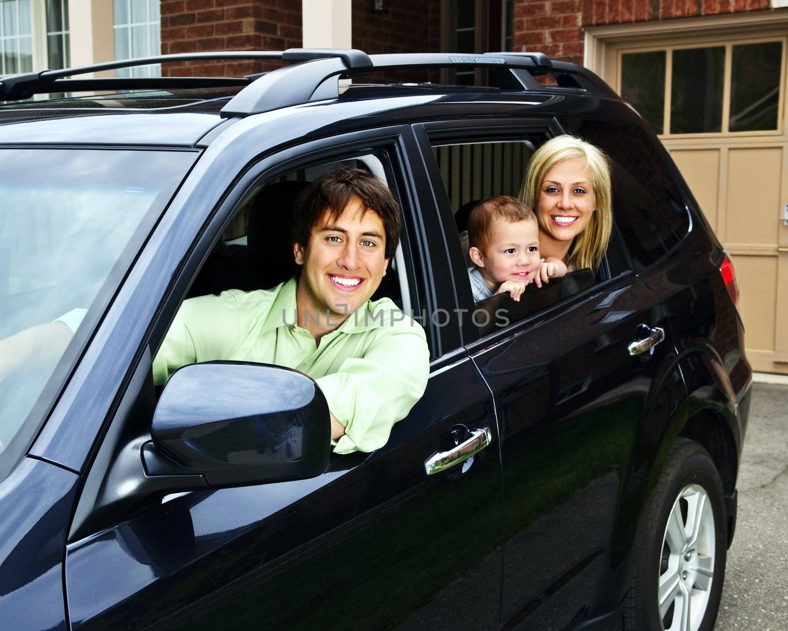 Happy young family sitting in black car looking out windows