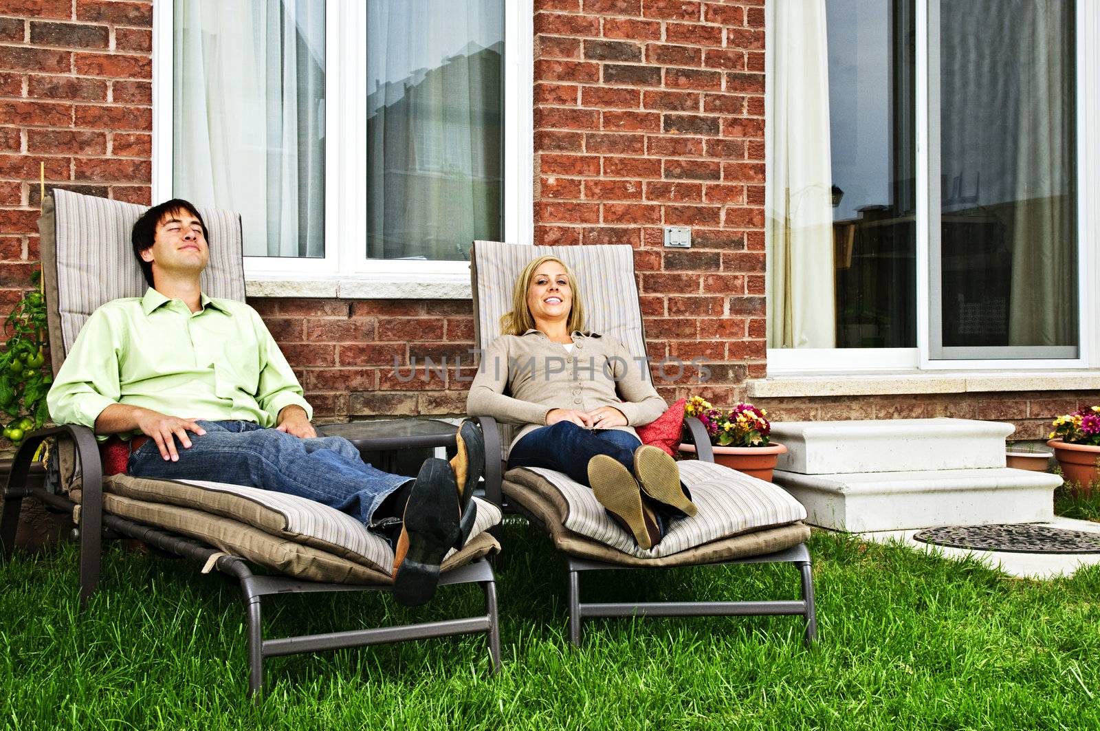 Happy couple in backyard of new home sitting on lounge chairs