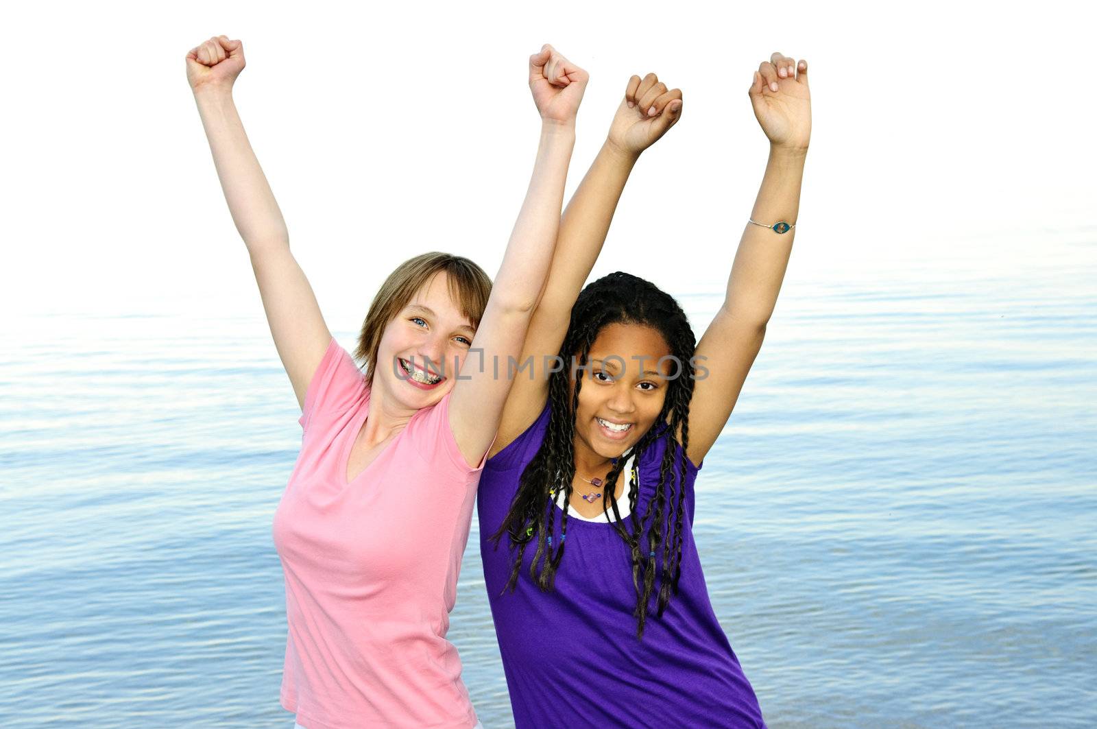 Portrait of two teenage girl friends raising arms