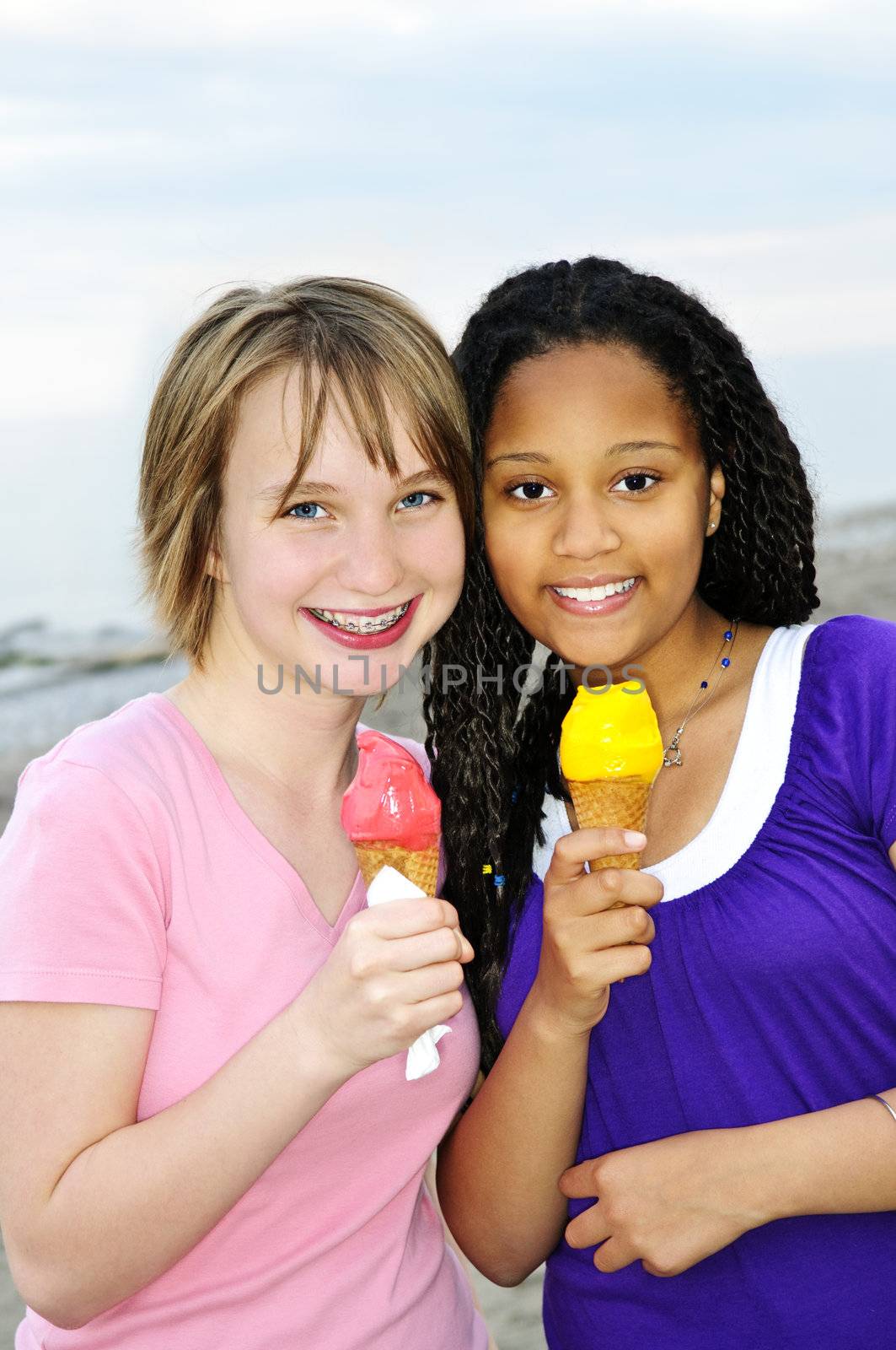 Portrait of two teenage girls eating ice cream cones