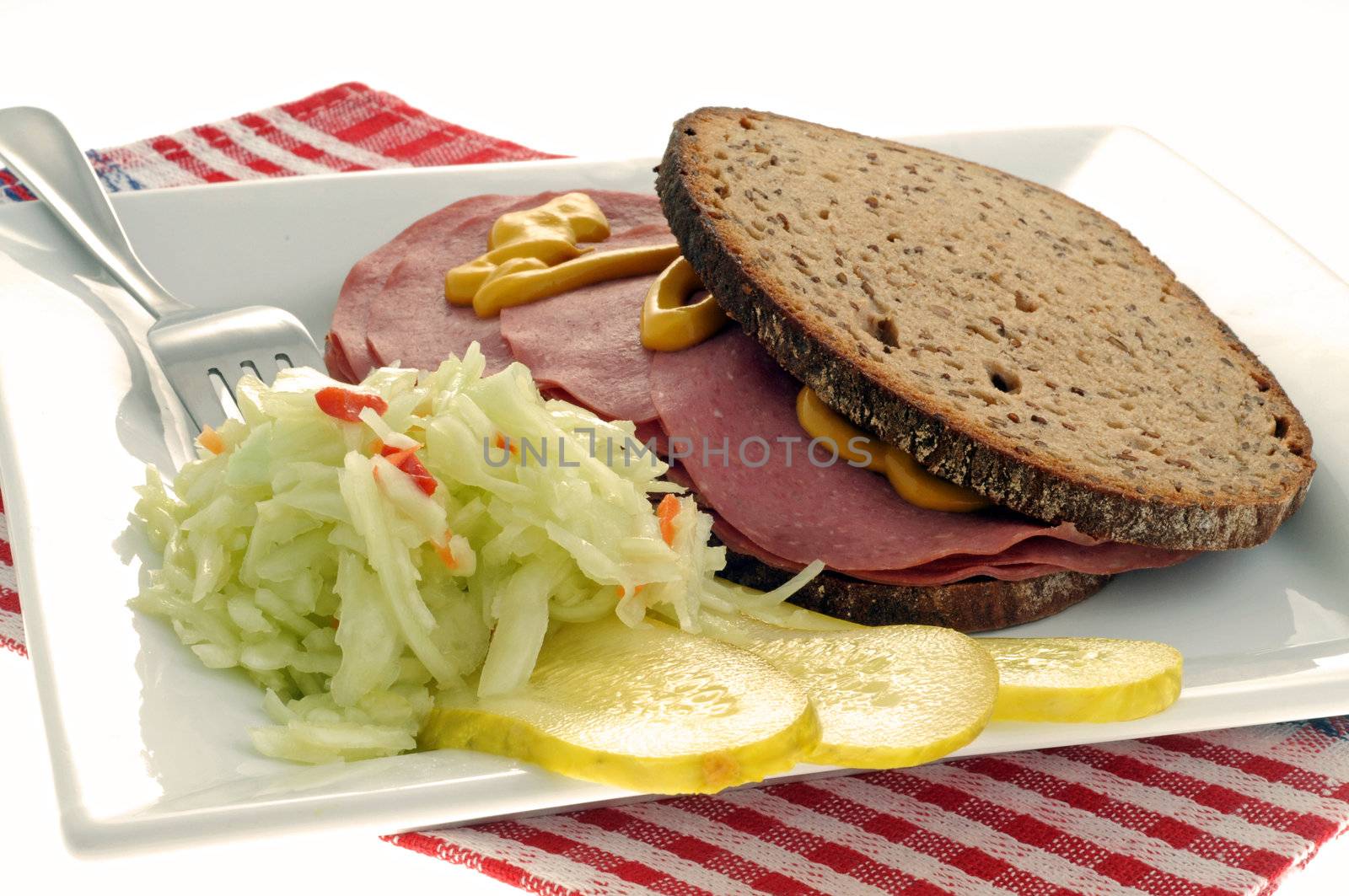 Coleslaw and pickles accompanying a deli sandwich.