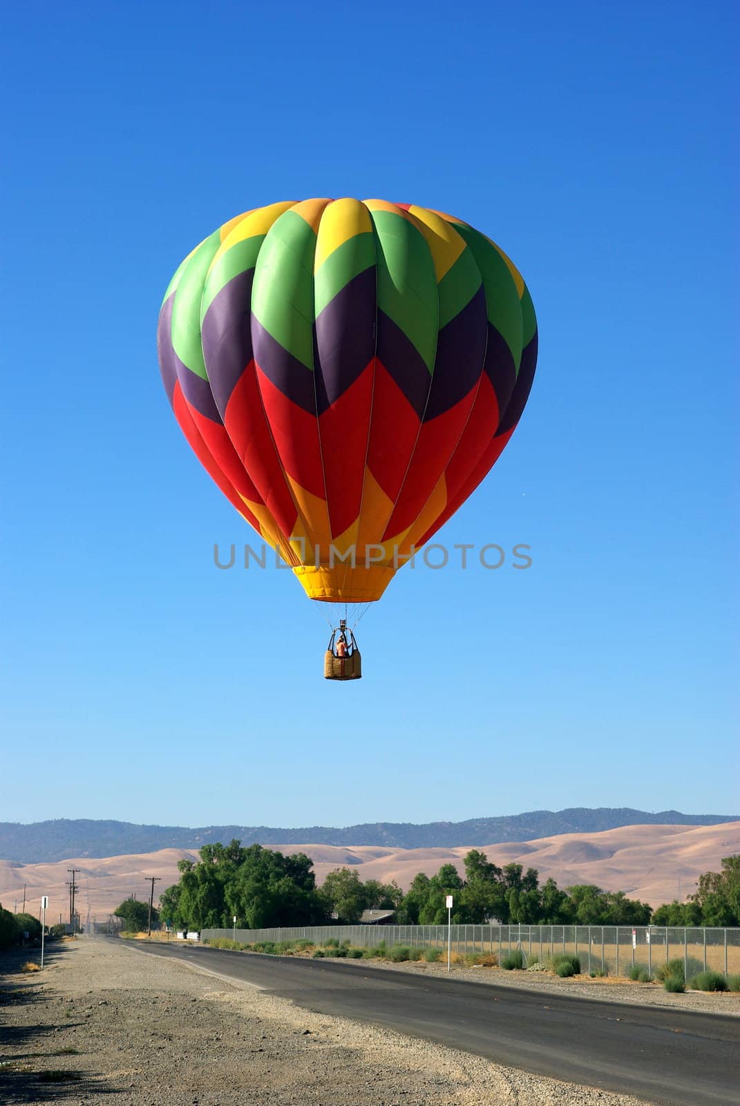 A multi colored Hot Ait Balloon coming in for a landing.