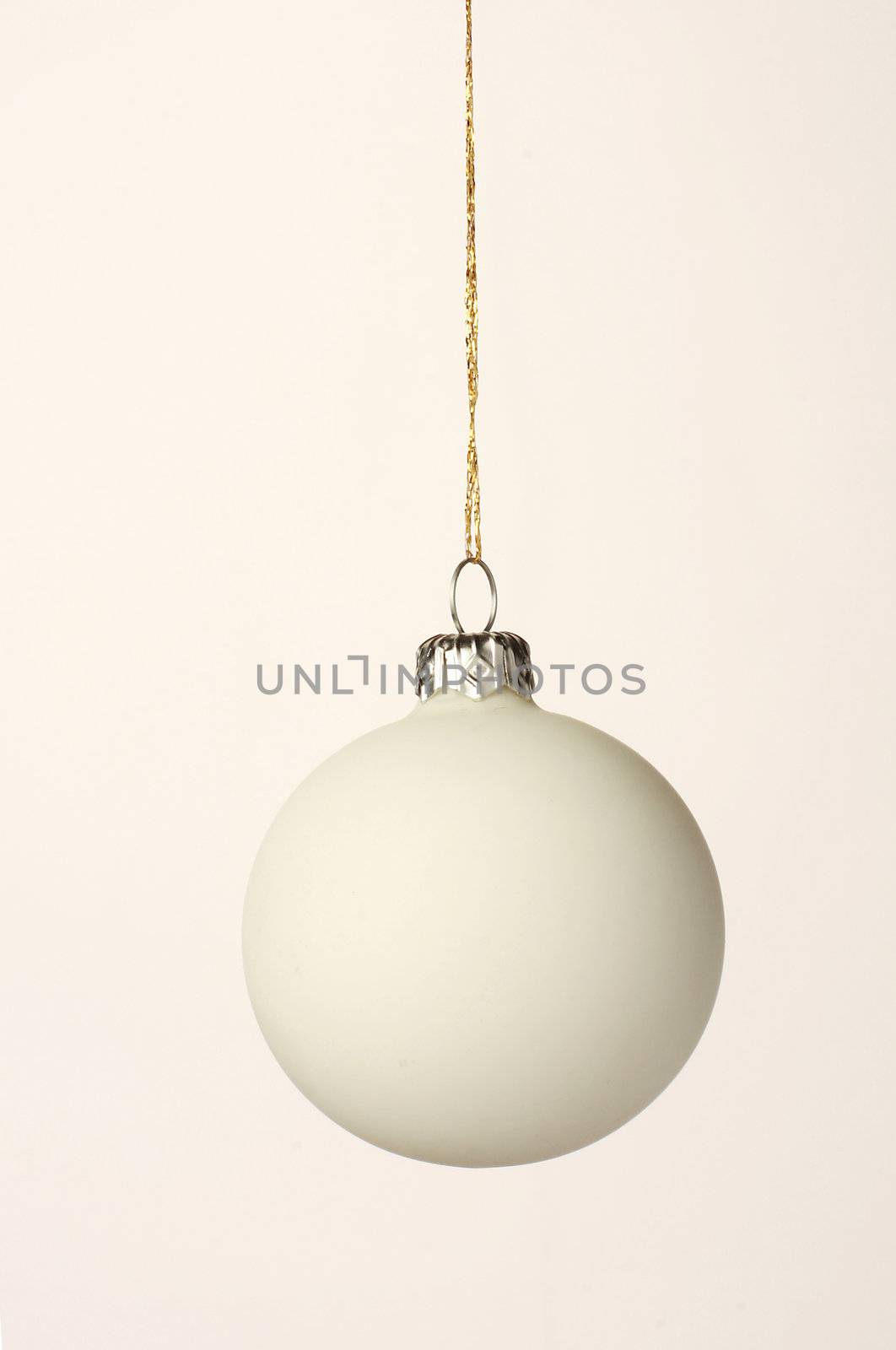 White christmas orb shot on white, hanging on a gold thread