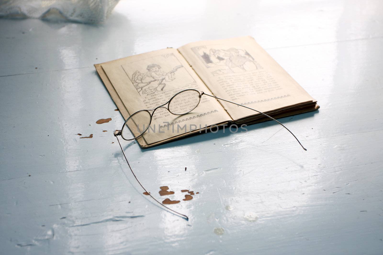 old fashioned reading glasses on top of an old book on a table 