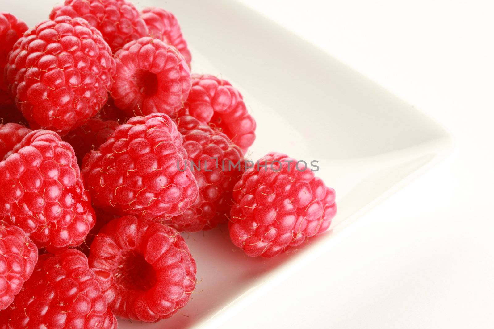 Raspberries on white dish, shot in studio isolated on white