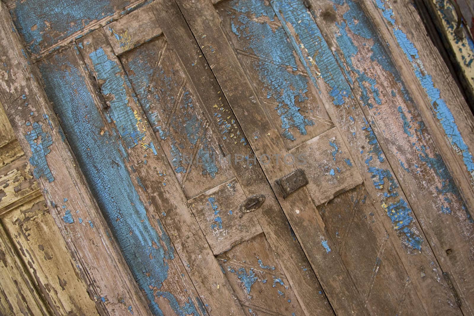 An antique painted blue door that is made out of weathered wood.