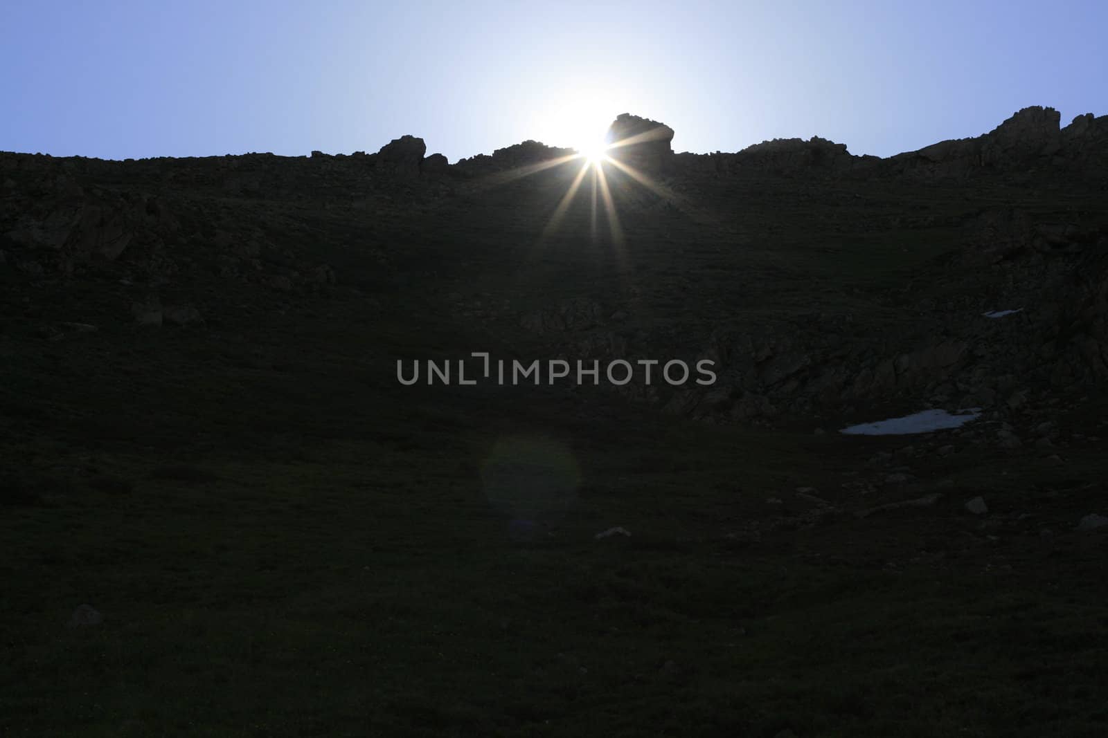 Sun peaking out from behind rock