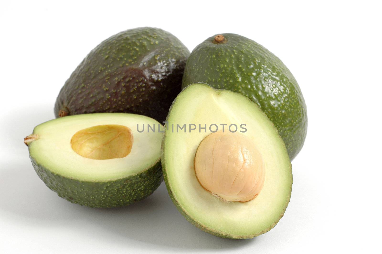 Ripe avacados against a white background with one sliced.