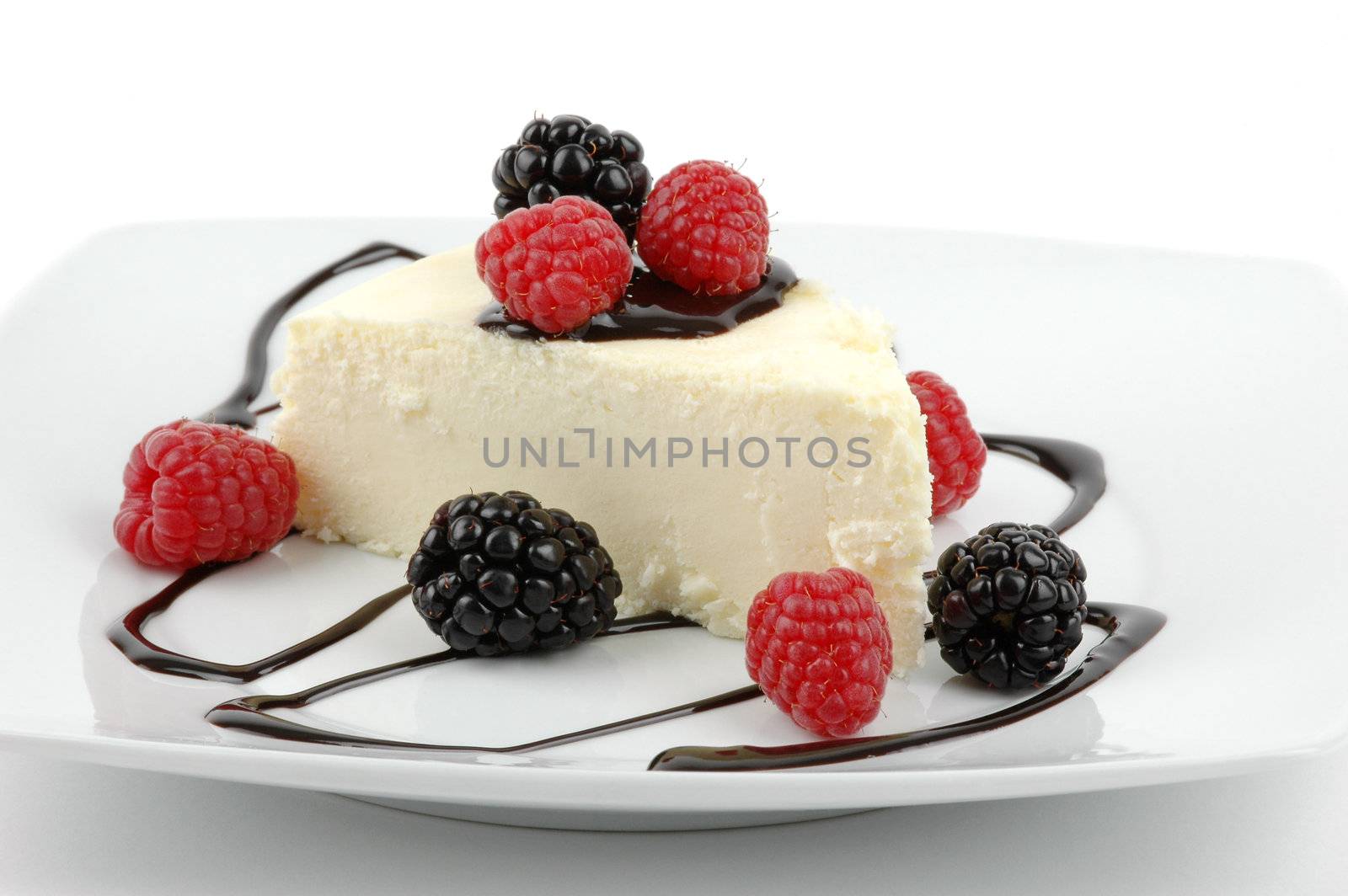 Creamy traditional cheesecake with berries and chocolate sauce.
